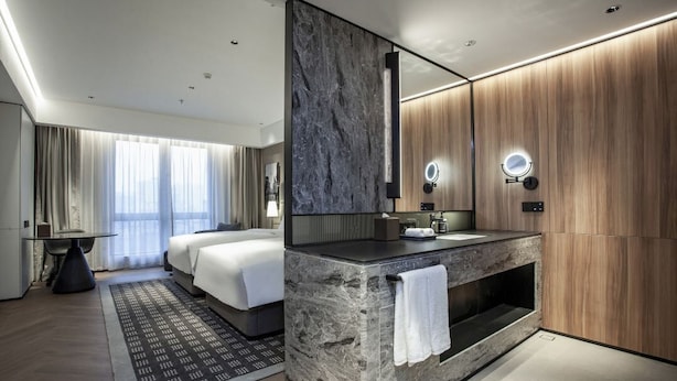 Une chambre d’hôtel moderne dotée d’un grand lit, d’une coiffeuse avec un miroir et d’un coin salon avec une table et des chaises.