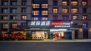 Un hôtel doté d’une façade moderne, d’une enseigne indiquant « Intercity Hotel » et d’un espace extérieur aménagé avec des sièges.