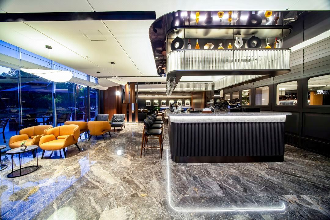 Um hall moderno com área de bar, assentos e vista através de grandes janelas.