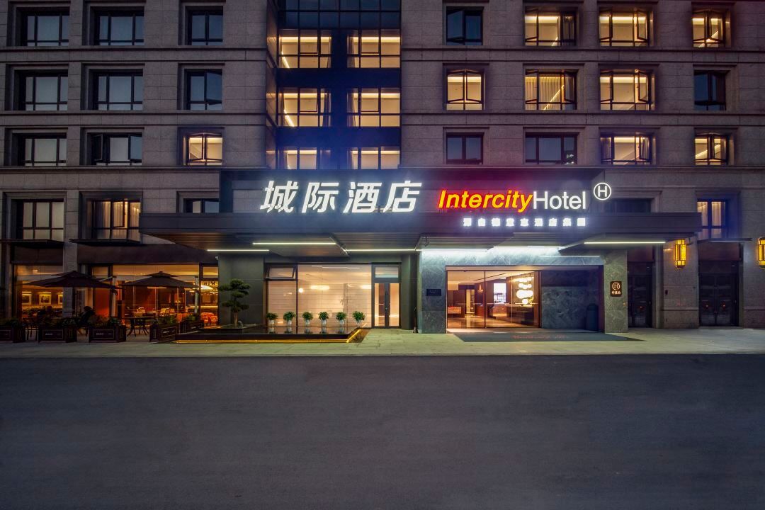 Um hotel com fachada moderna, com a placa 'Intercity Hotel' e área de estar ao ar livre.