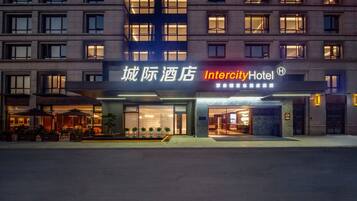 Um hotel com fachada moderna, com a placa 'Intercity Hotel' e área de estar ao ar livre.