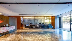 Un hall d’entrée moderne avec un sol en marbre, un comptoir d’accueil et une grande fenêtre.