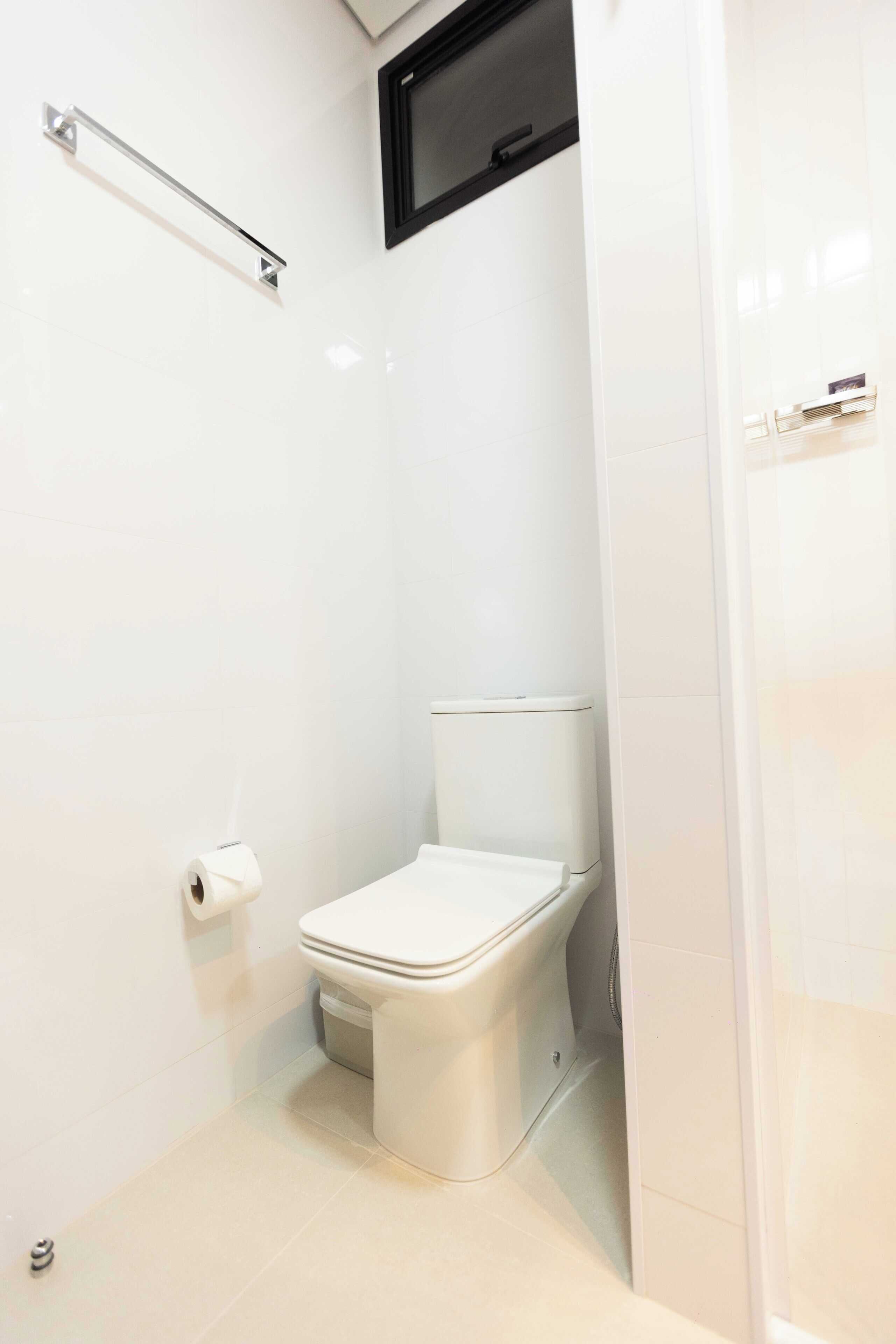 Un baño moderno con inodoro blanco, un perchero y un dispensador de papel higiénico.