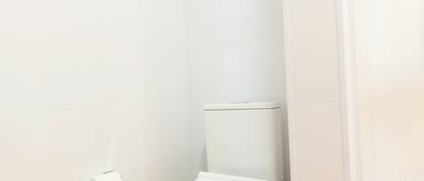 Une salle de bain moderne avec des toilettes blanches, un porte-serviettes et un support à papier toilette.