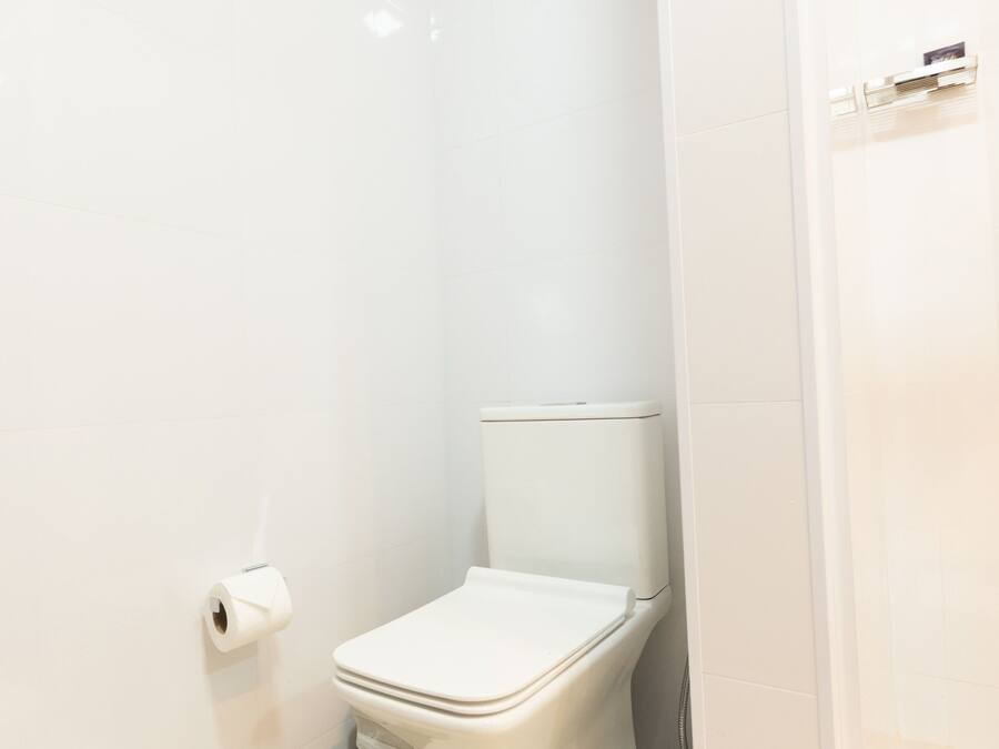 Un baño moderno con inodoro blanco, toallero y dispensador de papel higiénico.