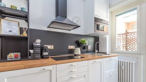 A modern kitchen with white cabinets, a wooden countertop, a built-in stove, and a window with a view of the outside. - Rhome Vatican Rooms (Rome)