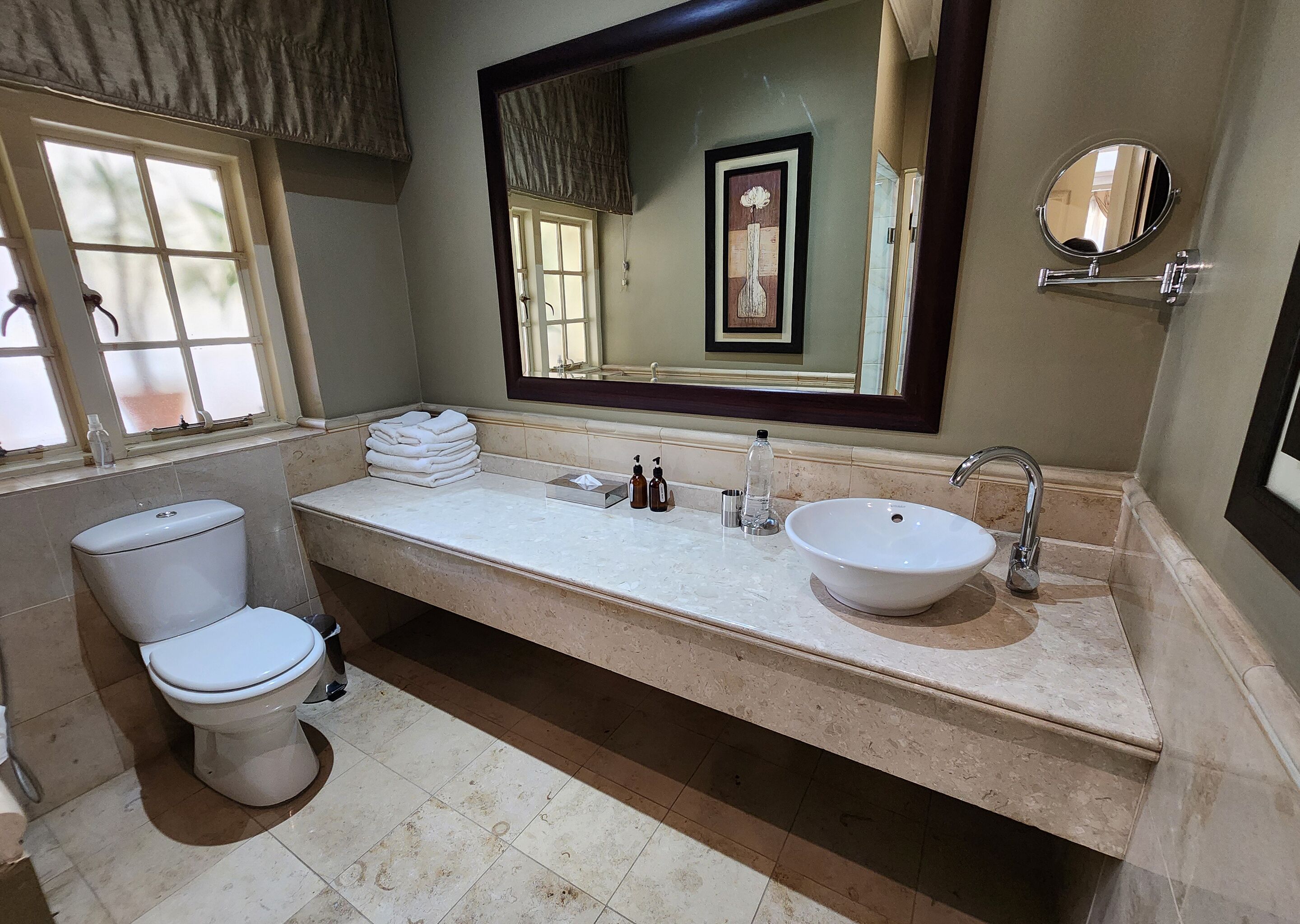 A bathroom with a toilet, a sink, a mirror, and a window.