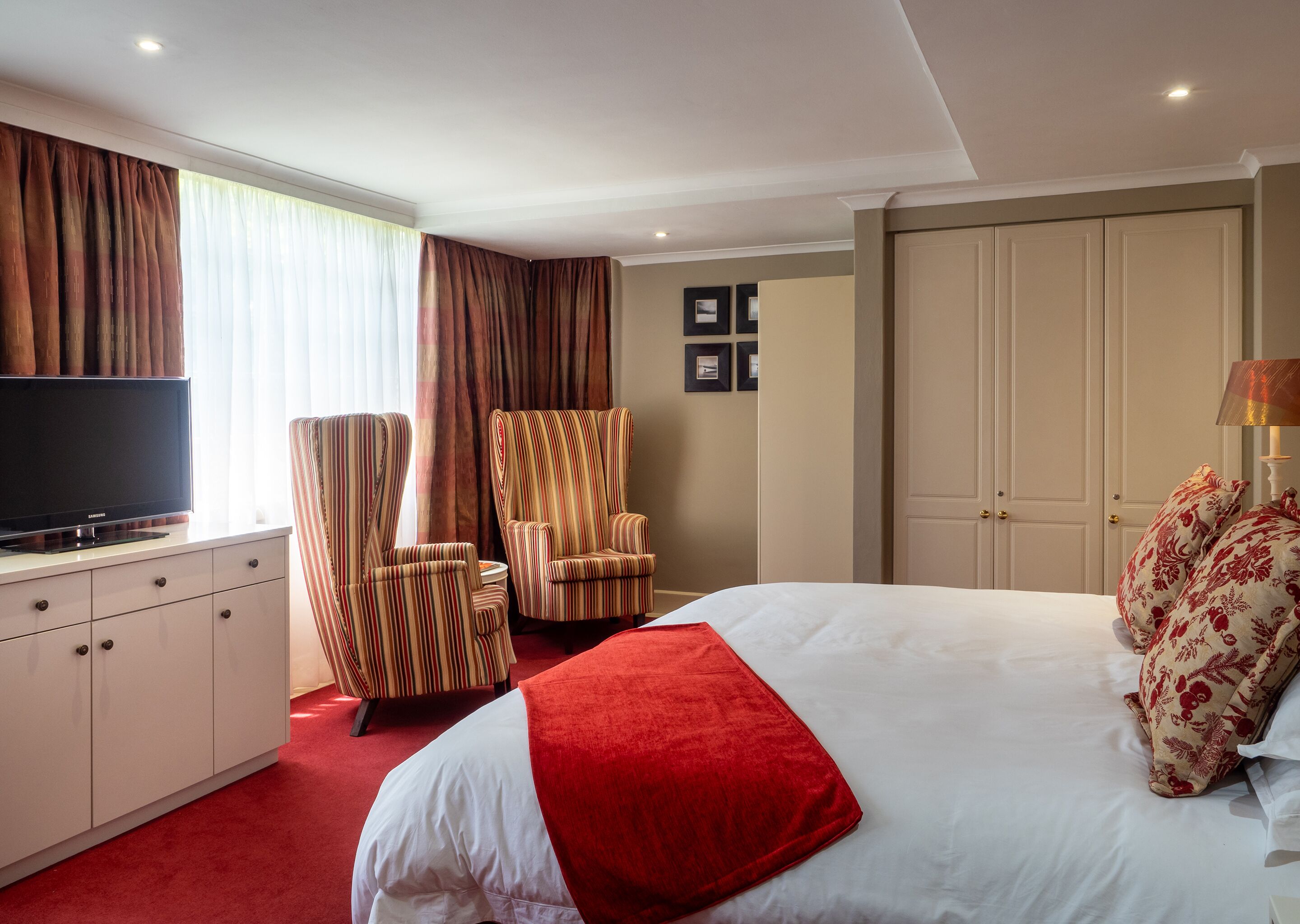 Ein Hotelzimmer mit einem Bett, einem Fernseher auf einem Schrank, einem Sessel und einem Kleiderschrank.