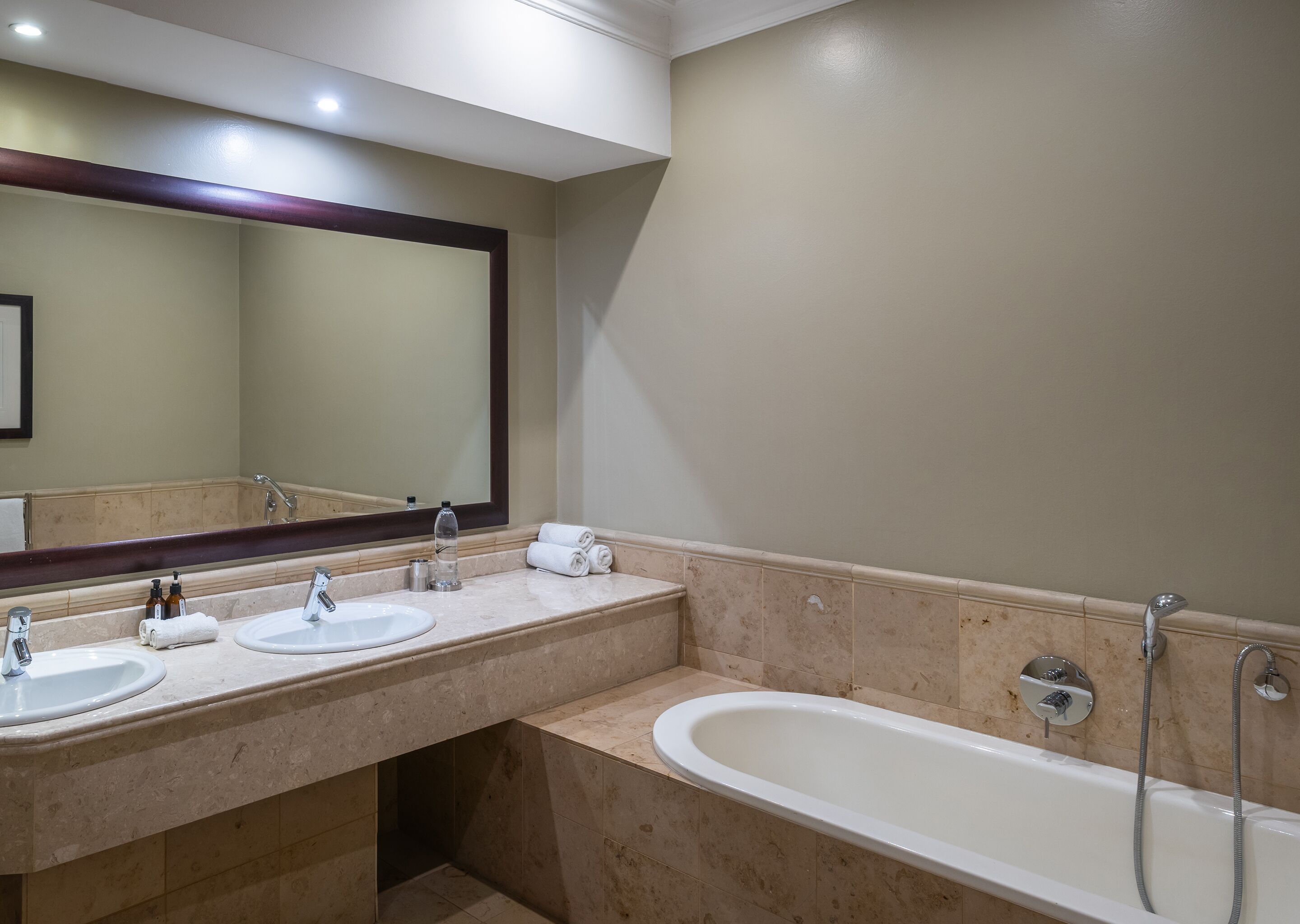 A bathroom with two sinks, a large mirror, and a bathtub.