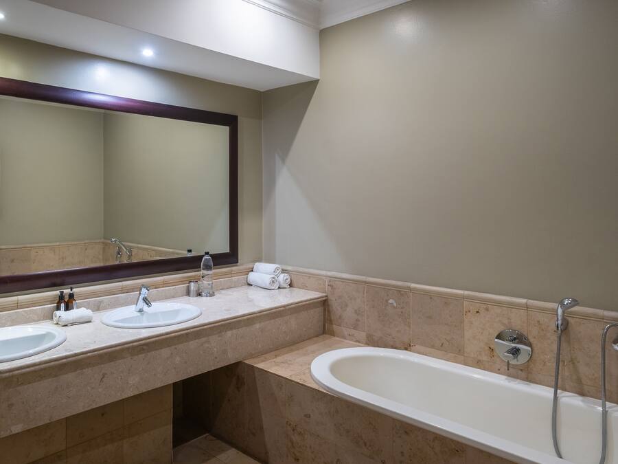 A bathroom with two sinks, a large mirror, and a bathtub.