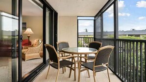 Ein Balkon mit Glastisch und Stühlen, einer Couch und einer Lampe.