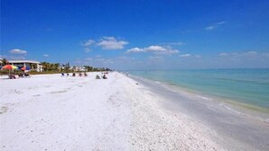 Una spiaggia con sabbia bianca, acqua cristallina e alcuni ombrelloni.
