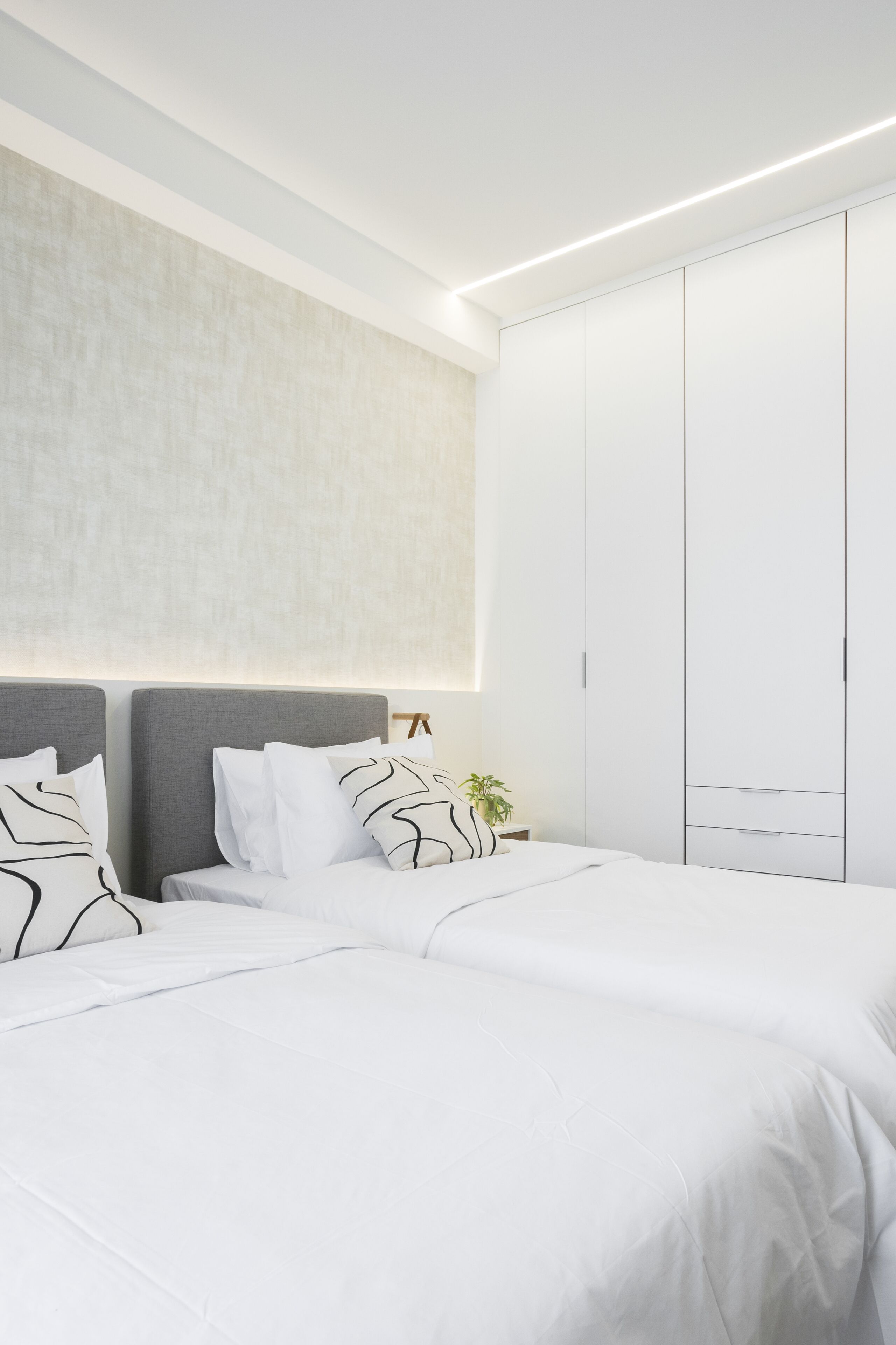 Ein modernes Schlafzimmer mit einem großen Bett, einem Kleiderschrank und einer Wandleuchte.
