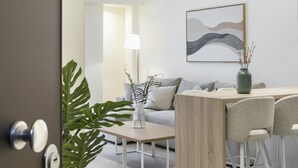 Een moderne woonkamer met een houten eettafel, een grijze bank en een potplant.