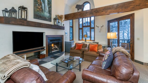A cozy living room with a fireplace, leather sofas, and a large TV. - Kayenta 7-Curate Telluride, Perfect SkI In/Out, Lift 4, Hot Tub, Fireplace (Mountain Village)