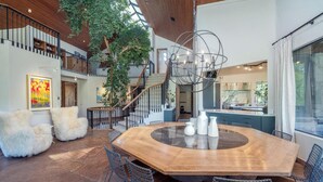 A spacious dining area with a large wooden table, surrounded by chairs, and a staircase leading to an upper level.