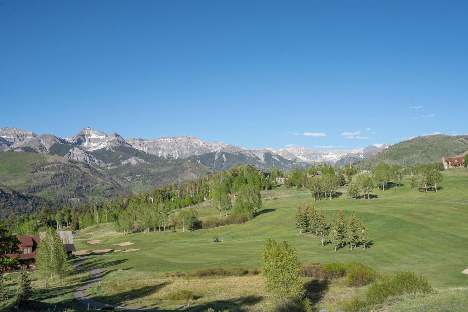 A mountainous landscape with a golf course, houses, and a clear sky.