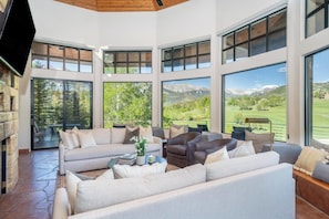 A spacious living room with a large sofa, armchairs, and a coffee table. Large windows offer views of a mountainous landscape. - Singletree-Paragon by Curate Telluride-Pickleball, Pool Tbl, Hot Tub, Ping Pong (Mountain Village)