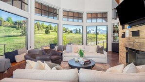 A spacious living area with large windows, a fireplace, and leather sofas.