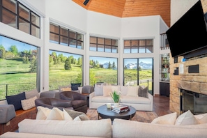 A spacious living area with large windows, a fireplace, and leather sofas.