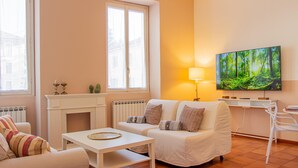 A cozy living room with a fireplace, a sofa, a coffee table, and a TV mounted on the wall. - La Ringhiera Fiorita 201 Autodromof1 Villa Reale (Monza)