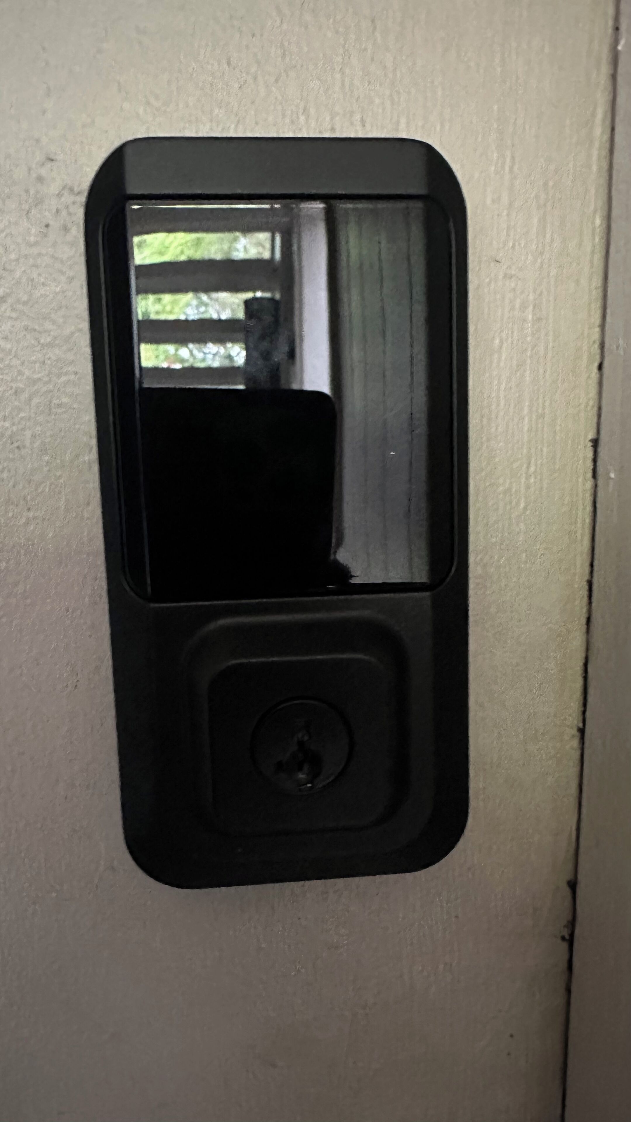 A black intercom mounted on a beige wall.