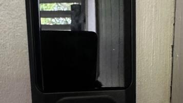 A black intercom mounted on a beige wall.