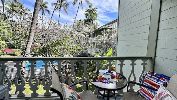 Un balcon donnant sur une piscine, des palmiers et un immeuble doté d’un balcon.
