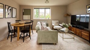 Una sala de estar moderna con una mesa de comedor, sofá, televisor y obras de arte.