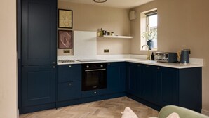 Una cocina compacta con armarios azul oscuro, una encimera blanca y un horno empotrado.