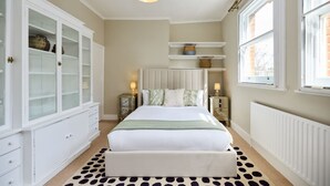 A bedroom with a bed, a white cabinet, a radiator, and a window. - The Fulham Town House - Spacious 4BDR House with Garden (London)