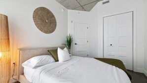 A bedroom with a bed, two doors, a wall-mounted circular decoration, and a plant. - Le Downtown (rooftop pool and gym) (Québec)