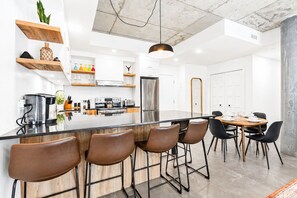 Une cuisine moderne dotée d’un îlot central, de tabourets de bar et d’un coin repas avec une table ronde.