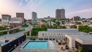 A rooftop pool area with a view of a cityscape, including various buildings and a highway. - Le Downtown (rooftop pool and gym) (Québec)