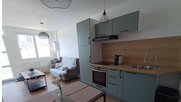 A modern kitchen with a dining area, a sofa, and a coffee machine. - - L'olivier - (Dozulé)