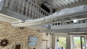 Una stanza con parete in pietra, una sedia di legno, un tavolo con una pianta e un quadro raffigurante una nave.