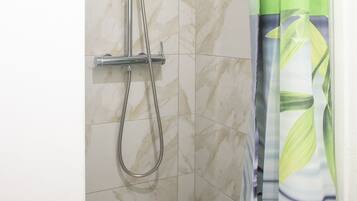 Een douche, handdoeken, zeep, shampoo