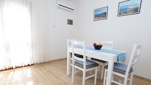 A dining area with a white table and chairs, a blue tablecloth, and a bowl of fruit on the table.