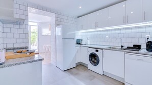 A modern kitchen with white cabinets, a built-in washing machine, and a granite countertop.