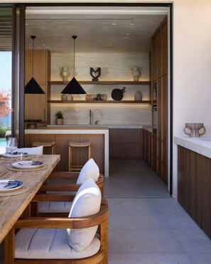 A modern kitchen with wooden cabinetry, a central island, and pendant lighting.