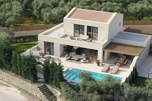 A modern two-story house with a swimming pool, outdoor seating, and a stone retaining wall.