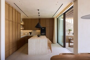 Eine moderne Küche mit Holzausbau, einer zentralen Kochinsel und einem großen Fenster.