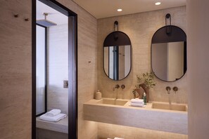 A modern bathroom with a large mirror, two sinks, and a shower area.