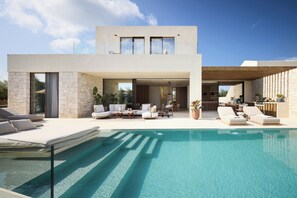 A modern house with a swimming pool, outdoor seating, and a kitchen area.