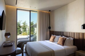 A hotel room with a bed, a desk, a chair, a TV, and a view of the outdoors.