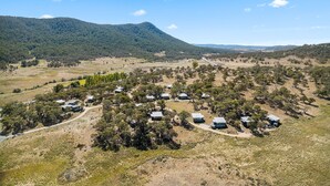 Un camping aislado con varias cabañas rodeadas de vegetación escasa y una montaña al fondo.