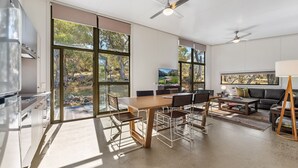 Una sala de estar moderna con ventanas amplias, un comedor y un sofá.