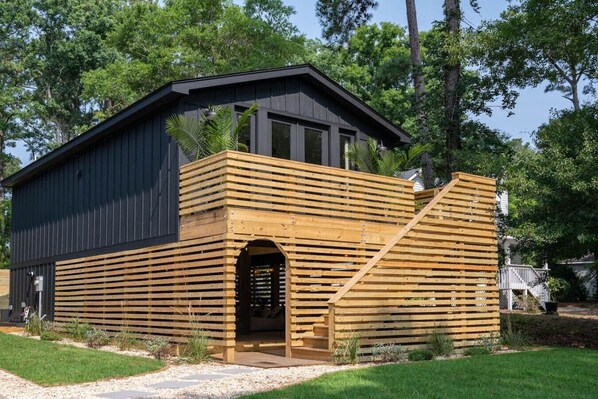 A modern building with a dark exterior and a wooden slatted entrance.