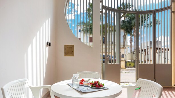 A round white table with two white chairs, a pitcher, a glass, and a plate of strawberries. - 3833 Residenza Nonna Lucia - Mono by Barbarhouse (Ugento)
