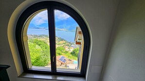 Una habitación con un amplio ventanal que ofrece vistas a un lago, vegetación y edificios lejanos.